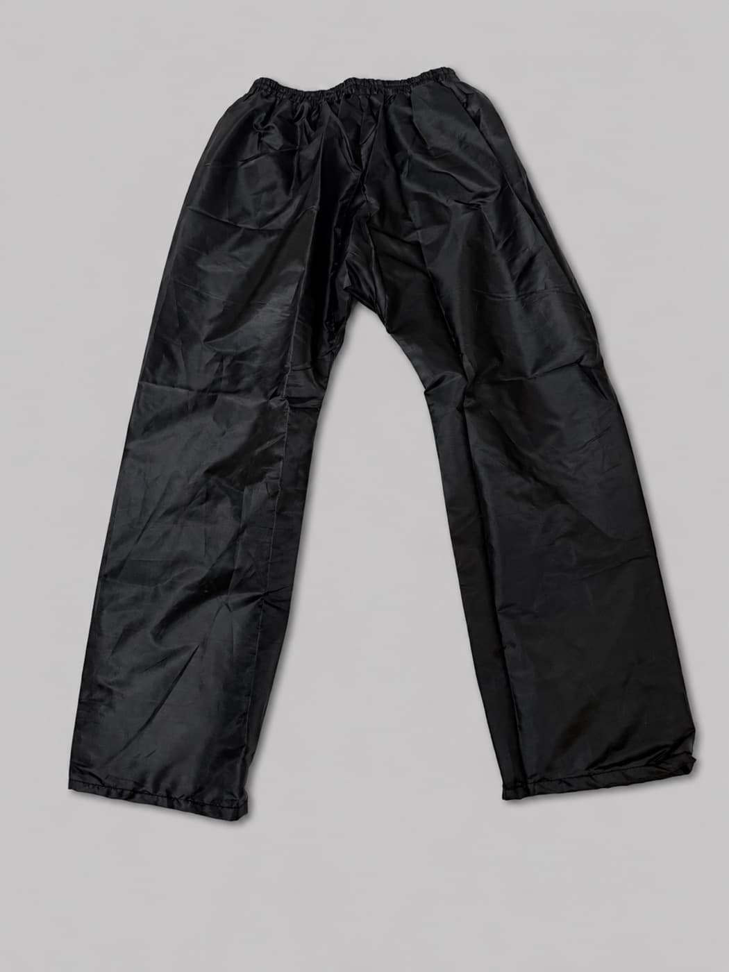 Black waterproof rain pants with elastic waist—lightweight nylon bottoms for rain suit and outerwear programmes